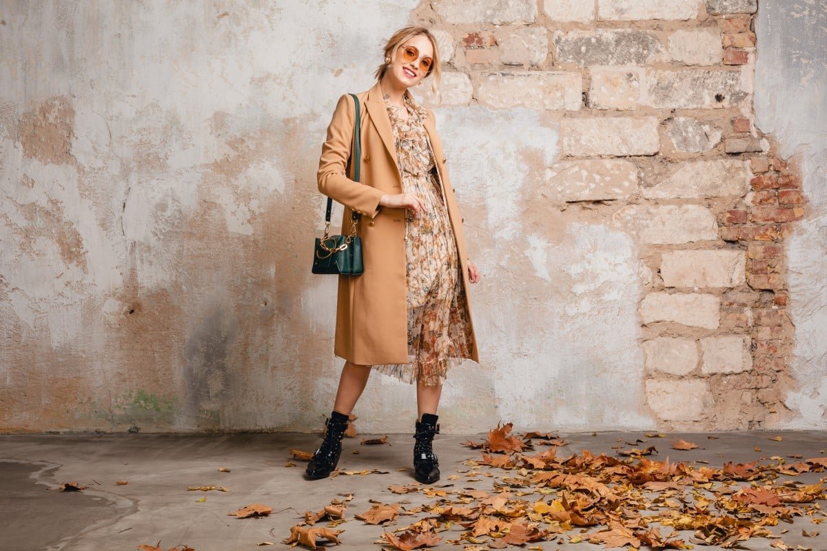Home attractive stylish blonde woman beige coat walking street against vintage wall 1.jpg