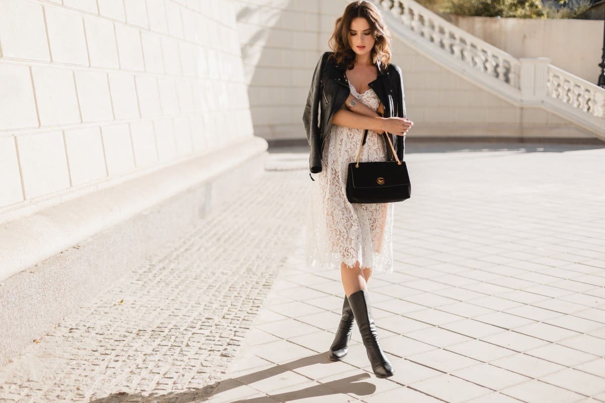 Home young stylish woman walking street fashionable outfit holding purse wearing black leather jacket white lace dress spring autumn style posing high leather boots 1.jpg